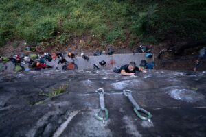 Climbers and belayers at Frank Curto Park. A set of hanging quick draws is in the forefront.